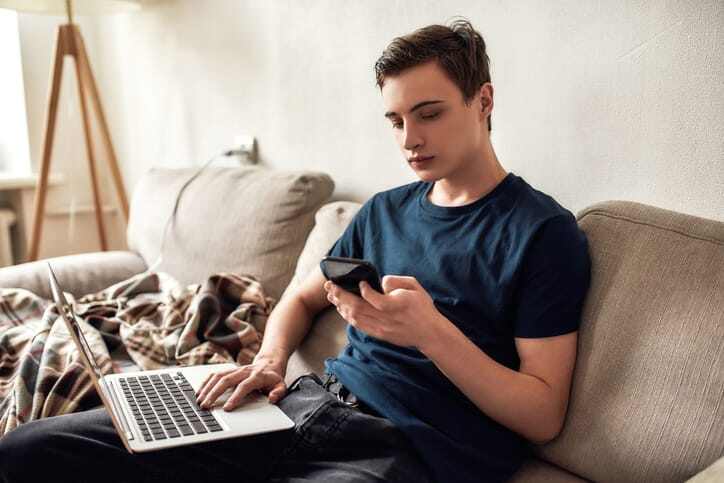 Teenager sitting with laptop and phone